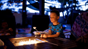 boy roasting marshmallow over fire in backyard